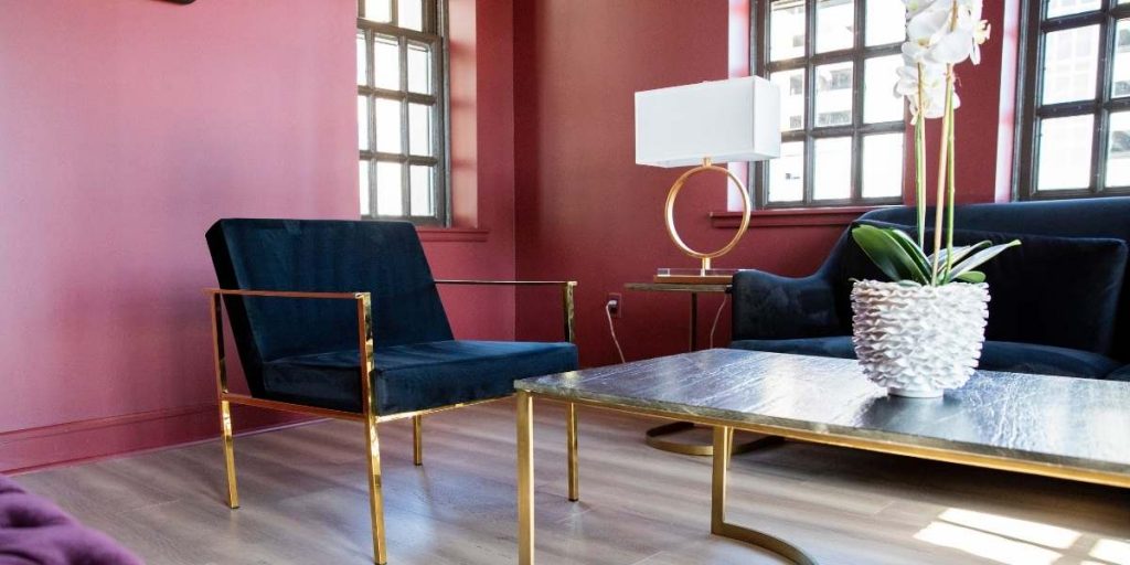 6 Colori per 6 Stili | Facile Ristrutturare Salone elegante con pareti rosa poltrone blu e tavolino con pianta