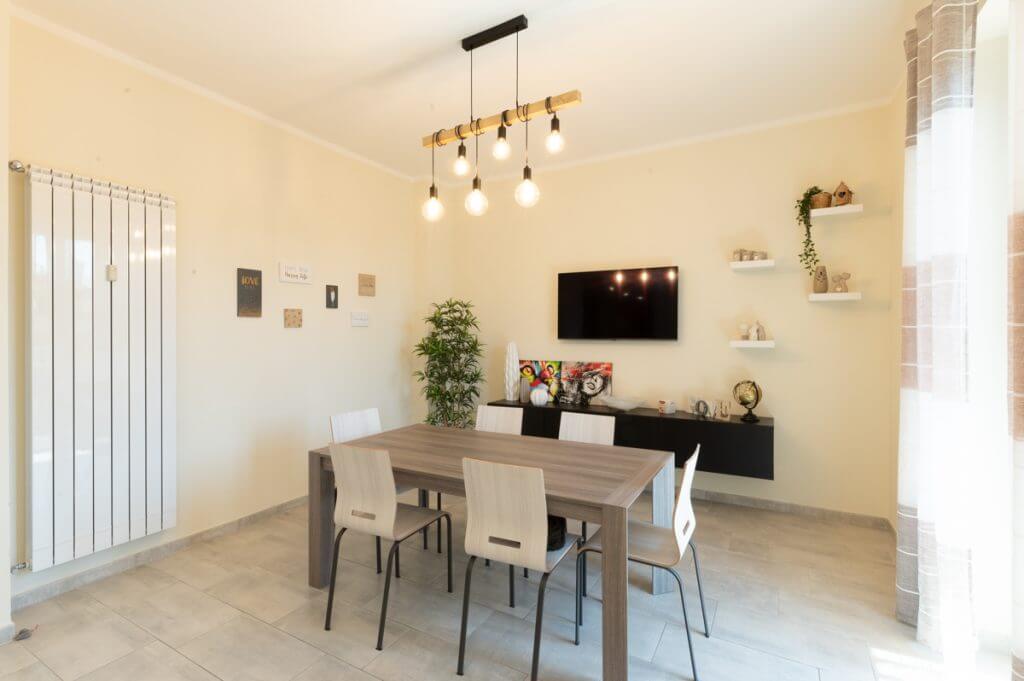 Ristrutturazione Zona pranzo con tavolo in legno e luci a sospensione.