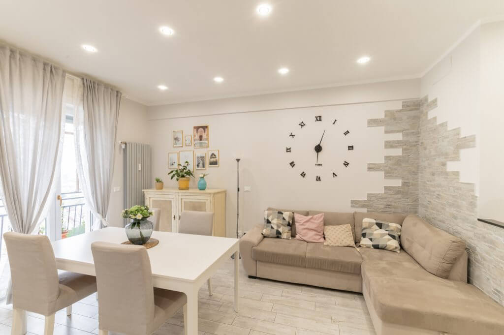 ristrutturazione casa Soggiorno con tavolo rettangolare bianco e divano angolare.