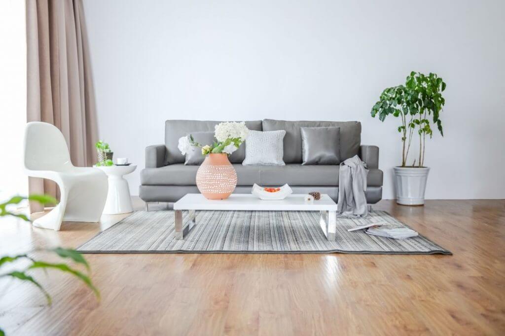 Rivestimenti in marmo e legno: come abbinarli | Facile Ristrutturare soggiorno con divano grigio, tavolino bianco e parquet.